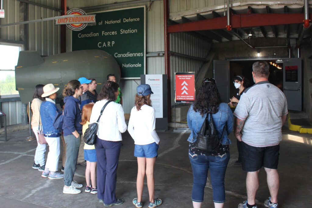 Families stand in front of a tour guide inside an industrial-style building.
