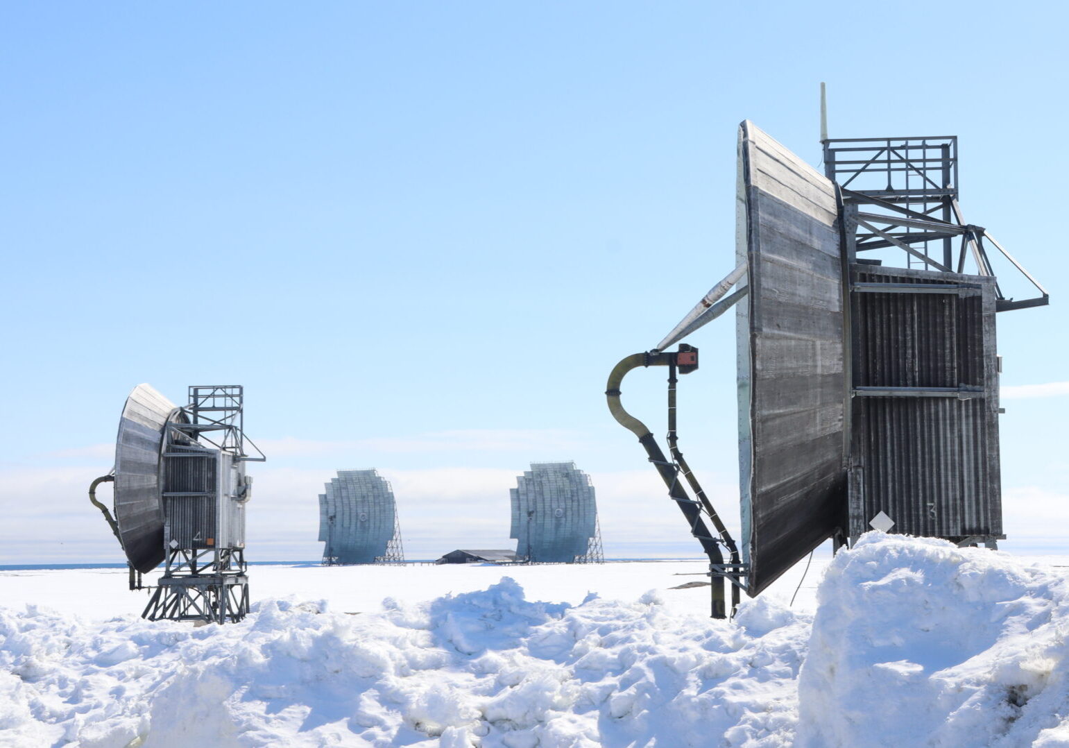 Multiple large grey parabolic antennae set in a snow-covered area.